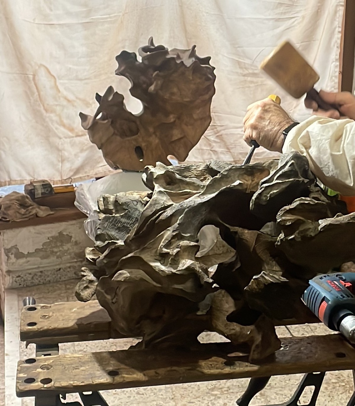 Paco Orejón tallando escultura en madera en su taller de Cudillero